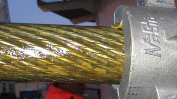 Close-up of a wire rope being lubricated with a pneumatic wire rope lubricator for deep strand lubrication and corrosion protection